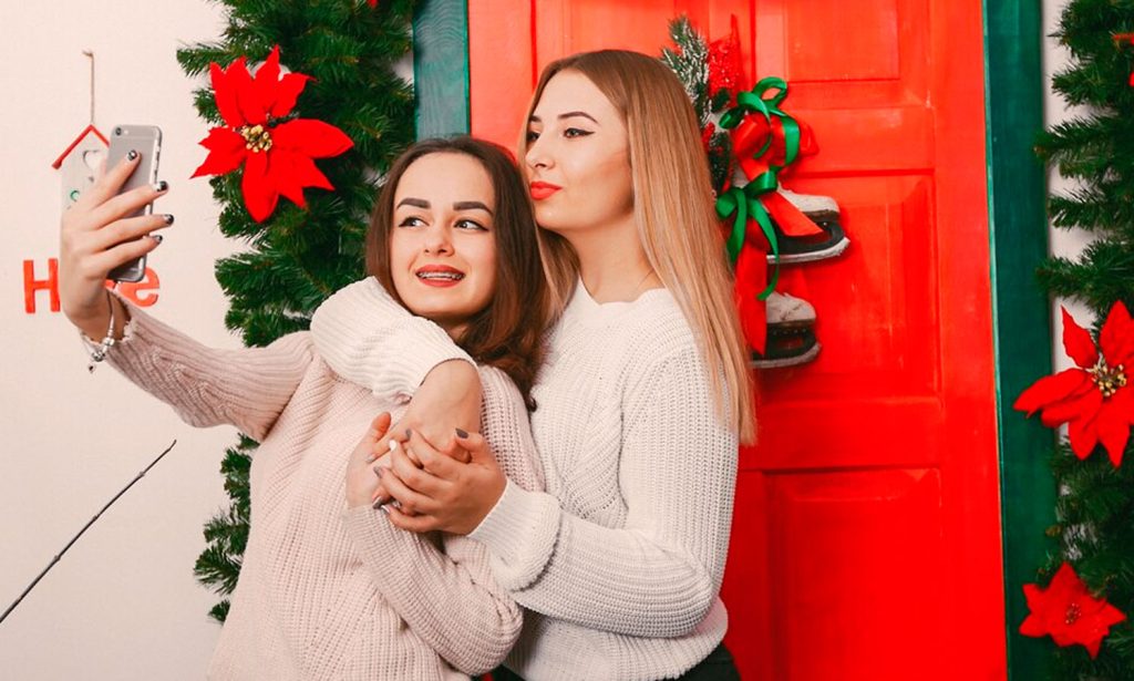 two women taking a picture of themselves in front of a red door