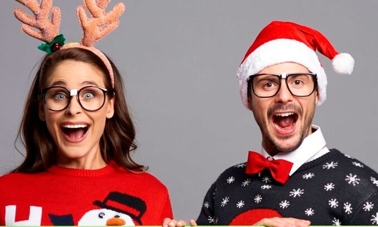 couple in christmas sweaters holding a sign with a snowman on it