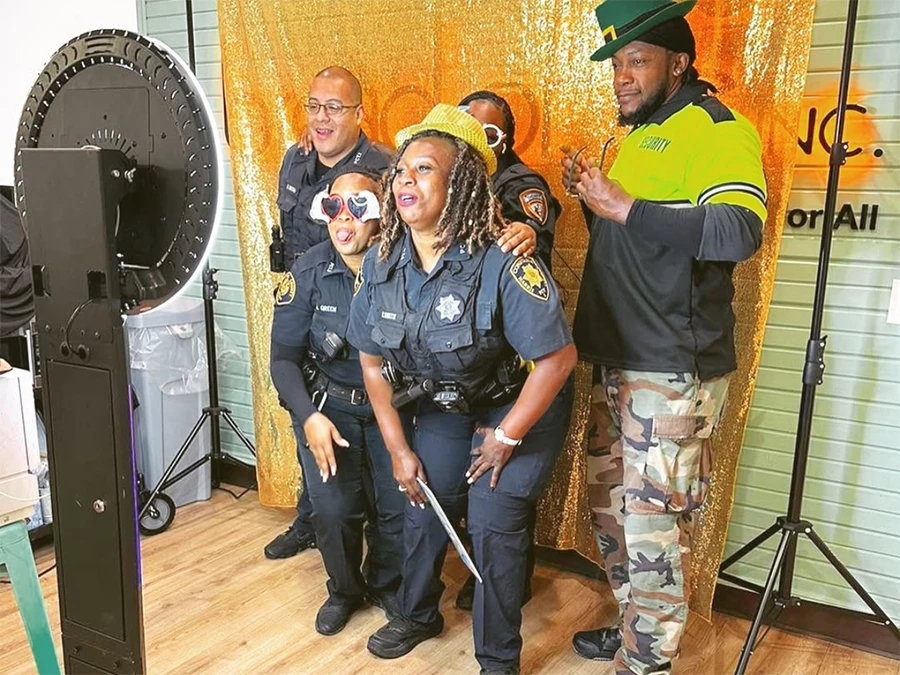 Police officers and security staff using 360 Photo Booth in Central Business District with a gold backdrop