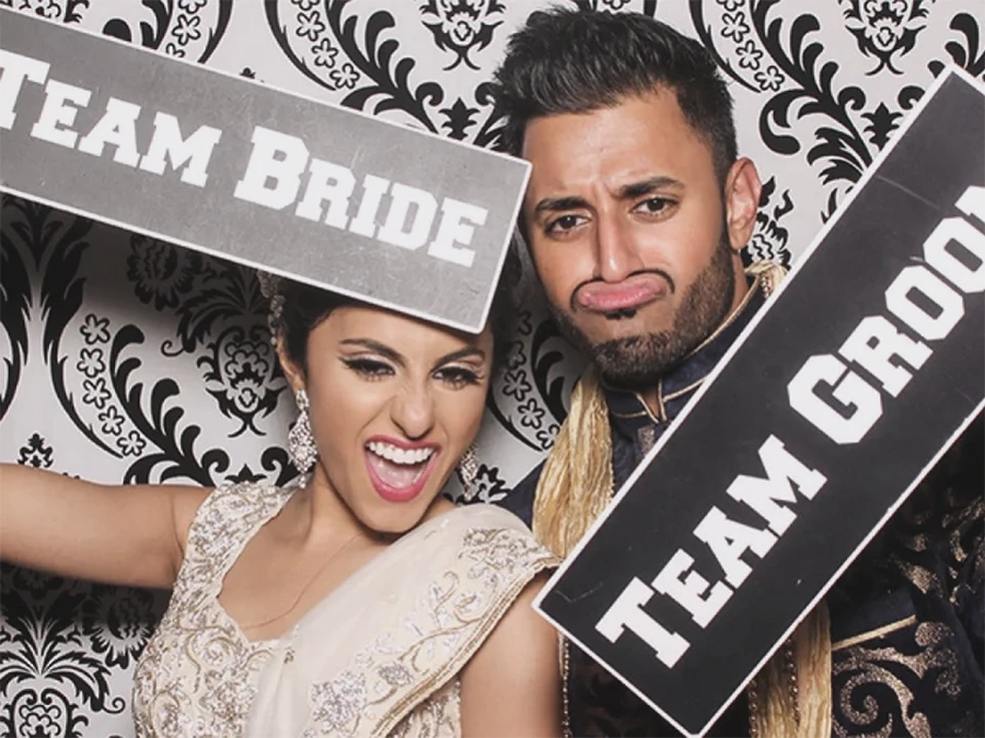 Bride and groom posing with 360 Spin Photo in Central Business District, holding Team Bride and Team Groom signs