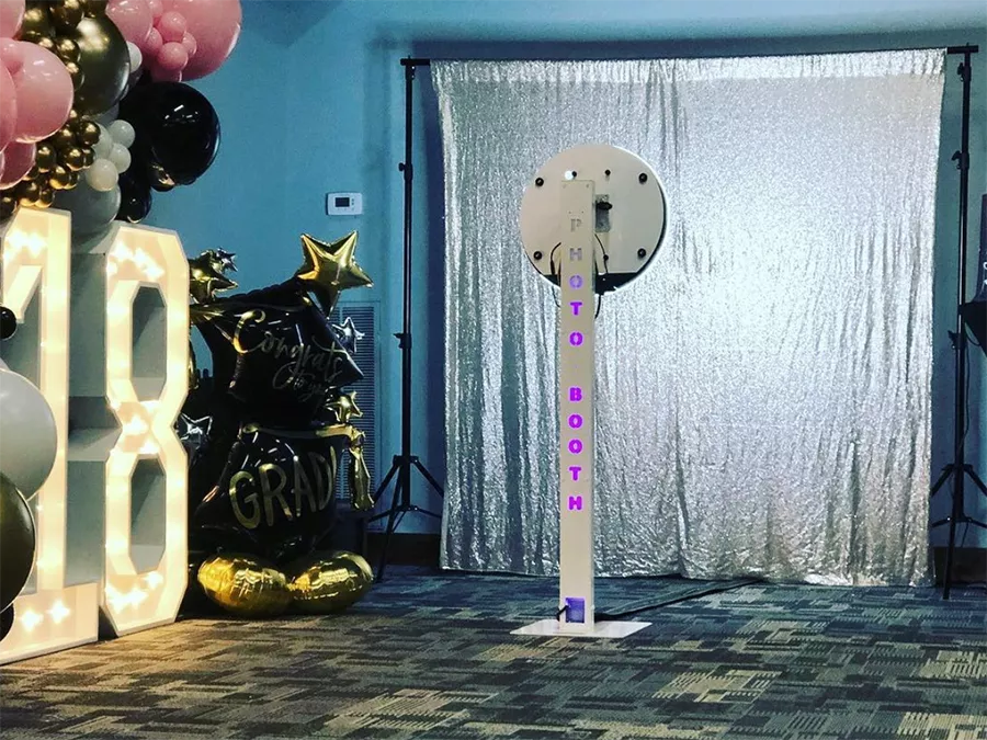 Elegant Rotating Photo Booth in Central Business District with a silver backdrop and festive decorations